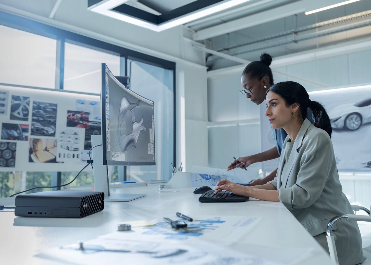 HP Z2 Mini G1i on a design studio desk next to a curved monitor, with two engineers at work